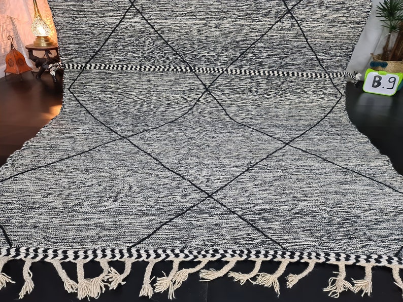 May include: Black and white diamond patterned rug with fringe. The rug has a woven texture and a simple design.