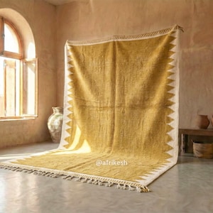 May include: A large, rectangular rug with a yellow and white geometric design. The rug has a fringe along the bottom edge and is displayed in a room with a window and neutral-toned walls. The rug is approximately 8 feet by 10 feet.