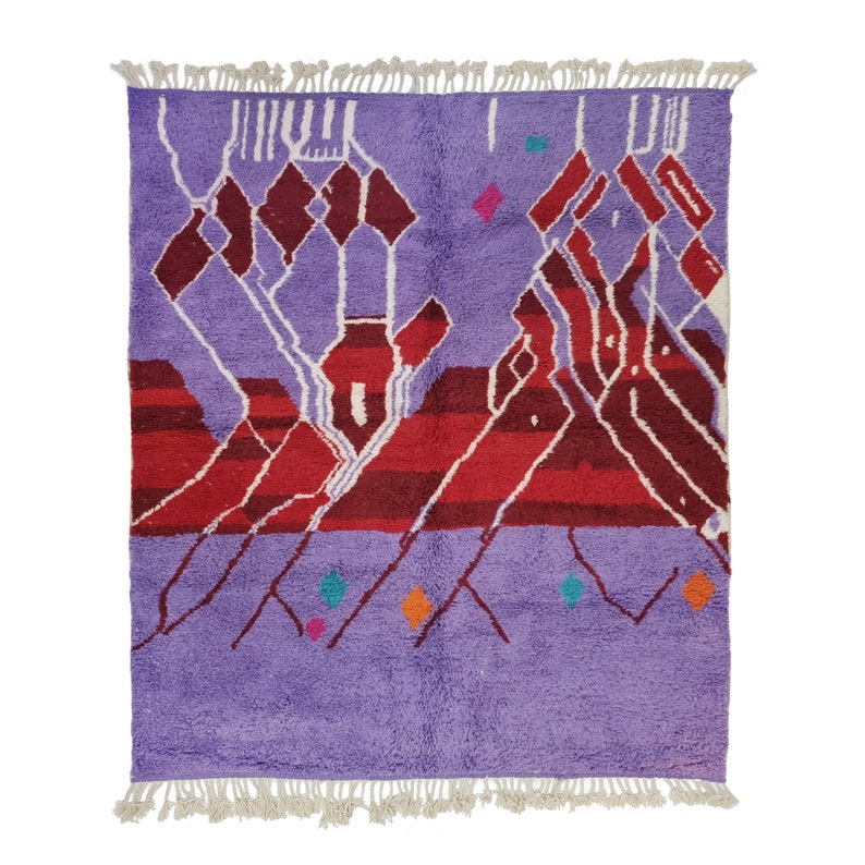May include: A purple and red Moroccan rug with a geometric pattern. The rug has a fringe border and is made of wool.