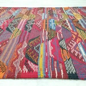 Pu&ograve; includere: Un tappeto rettangolare colorato con un design patchwork. Il tappeto presenta una variet&agrave; di colori, tra cui rosso, arancione, blu e bianco. Il design &egrave; geometrico, con un mix di strisce e forme. Il tappeto &egrave; realizzato in materiale tessuto.