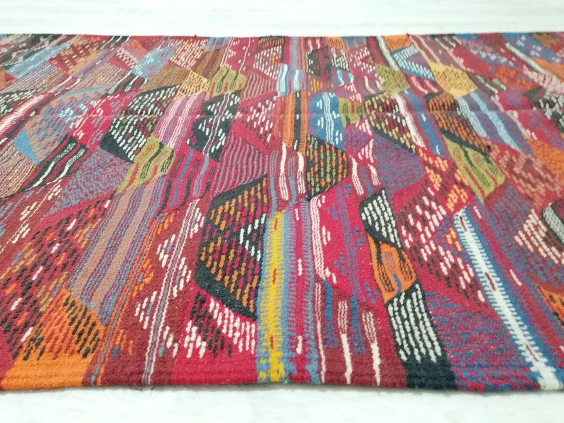 Pu&ograve; includere: Un tappeto rettangolare colorato con un design patchwork. Il tappeto presenta una variet&agrave; di colori, tra cui rosso, arancione, blu e bianco. Il design &egrave; geometrico, con un mix di strisce e forme. Il tappeto &egrave; realizzato in materiale tessuto.