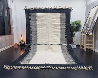 May include: Black and white striped rug with a white center and a black border. The rug has a fringe around the edges.