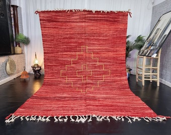 May include: A red and cream colored woven rug with a geometric pattern in the center. The rug has fringe on all sides.