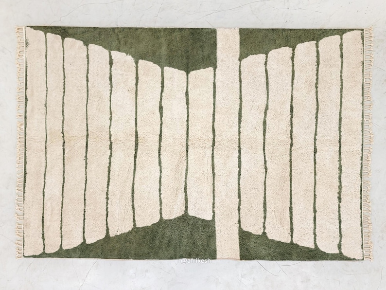 May include: A rectangular rug with a green and cream color scheme. The rug features a central green section with vertical cream-colored stripes. The rug has a textured appearance and a fringed edge, suitable for home decor.