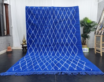 Puede incluir: Una alfombra marroquí azul y blanca con un patrón de diamantes. La alfombra tiene un borde de flecos y está hecha de lana.
