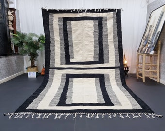 May include: Black and white striped rug with a geometric pattern. The rug has a fringe border.