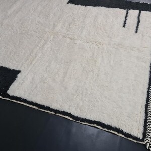 May include: A white rug with black geometric designs and fringe along the edges.