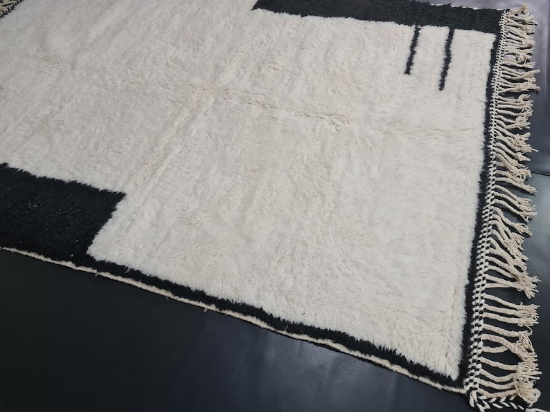 May include: A white rug with black geometric designs and fringe along the edges.