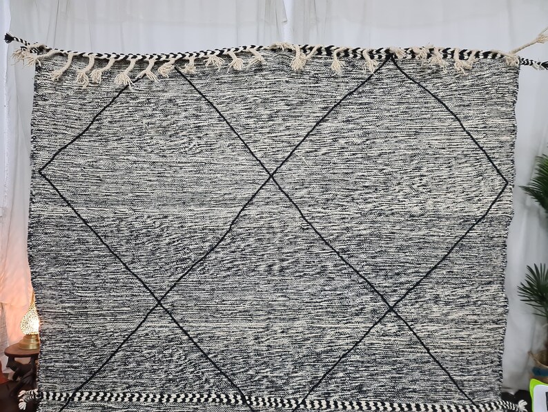 May include: Black and white rug with a diamond pattern. The rug has a fringe border.