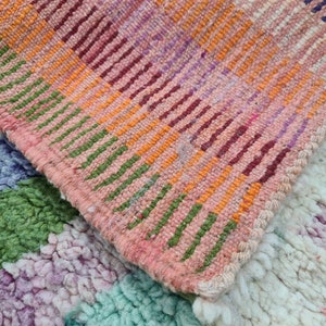 May include: Two woven rugs with a colorful striped pattern. The top rug is pink, orange, green, and purple. The bottom rug is white, green, purple, and blue.