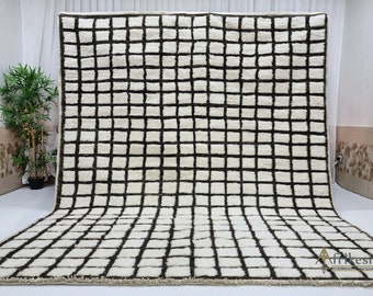 May include: A white and brown geometric rug with a grid pattern. The rug has a fringe border.