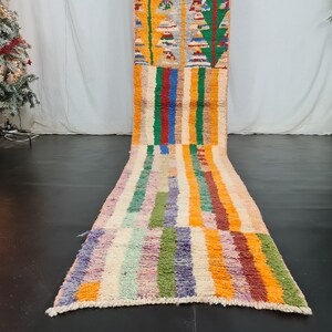 May include: A colorful Moroccan rug with a striped pattern in shades of orange, yellow, green, blue, and purple. The rug is made of wool and has a hand-woven texture.