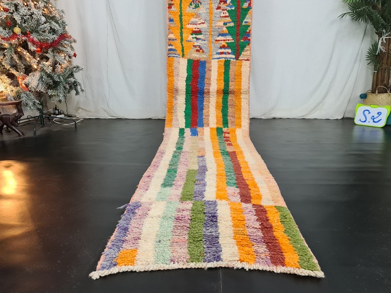 May include: A colorful Moroccan rug with a striped pattern in shades of orange, yellow, green, blue, and purple. The rug is made of wool and has a hand-woven texture.