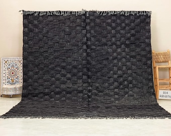 May include: A black and gray Moroccan rug with a geometric pattern. The rug has a fringe border and is made of wool.