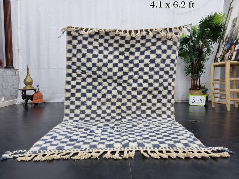 Op de afbeelding: Een blauw-wit geblokt tapijt met franjes. Het tapijt is 4,1 x 6,2 voet.