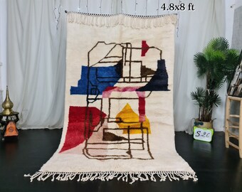 Könnte beinhalten: Ein weißer Wollteppich mit einem geometrischen Muster in Rot-, Blau-, Gelb- und Brauntönen. Der Teppich hat einen Fransenrand und misst 1,46 x 2,44 Meter.