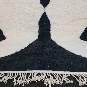 May include: Black and white rug with a unique abstract design and fringe trim.