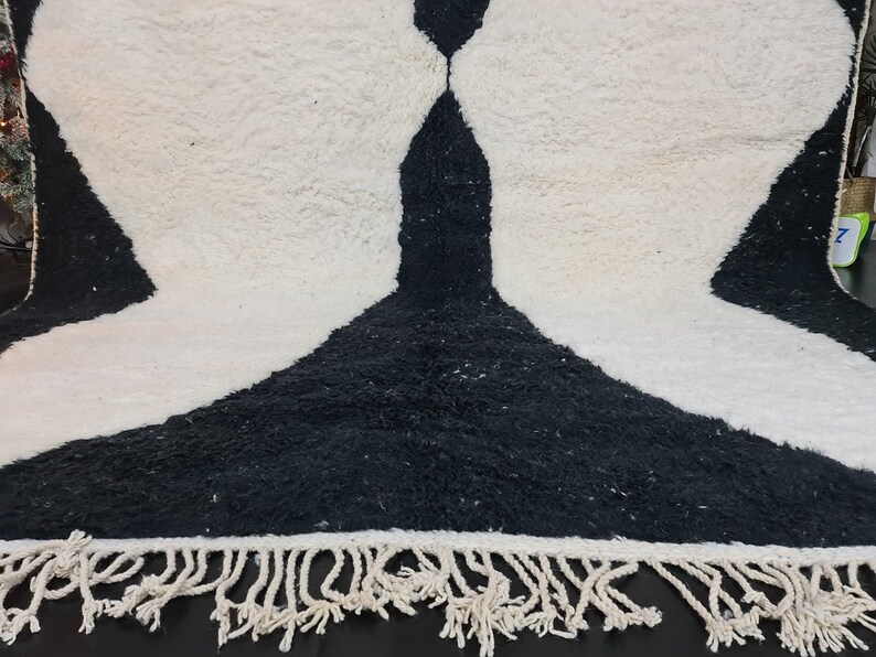 May include: Black and white rug with a unique abstract design and fringe trim.