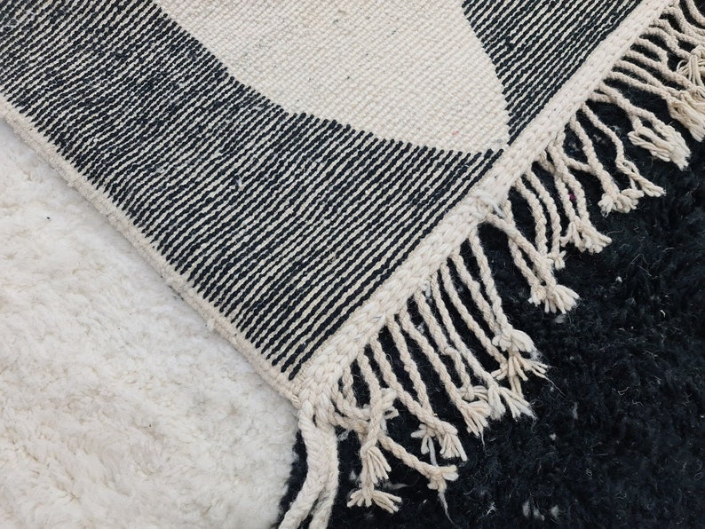 May include: Black and white patterned rug with a fringe border. The rug is made of wool and has a soft, textured feel.