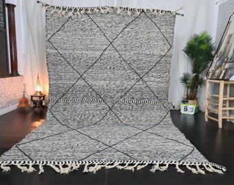 May include: A black and white Moroccan rug with a diamond pattern. The rug has a fringe border and is made of wool.