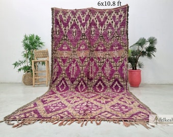 May include: A large, intricately patterned rug with a pink, brown, and cream color scheme. The rug has a geometric design and is approximately 6 feet by 10.8 feet.