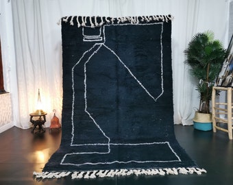 May include: A black and white Moroccan rug with a geometric design. The rug has a fringe border and is made of wool.