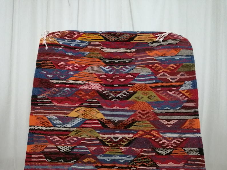 Pu&ograve; includere: Un tappeto colorato e fantasia con un design geometrico. Il tappeto presenta una variet&agrave; di colori, tra cui rosso, arancione, blu e giallo. Il design del tappeto &egrave; composto da forme e linee ripetute, creando un aspetto strutturato. Il tappeto &egrave; rettangolare e sembra essere fatto di tessuto tessuto.