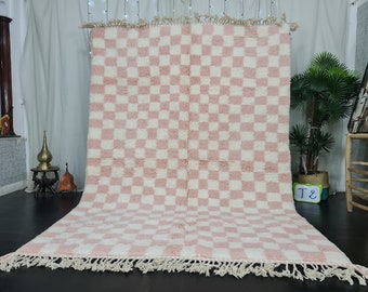 Puede incluir: Una alfombra de cuadros rosa y blancos con un borde de flecos. La alfombra está hecha de un material suave y esponjoso.