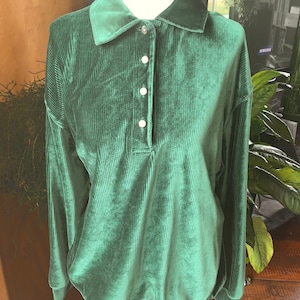 Green ribbed velour top. Buttons up 3/4 of the way up. Fits like a small-medium or a smaller large.