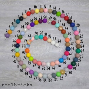May include: A colorful set of 84 round beads, numbered 1 through 84, arranged in a circle. The beads are made of silicone and come in a variety of colors, including red, blue, green, yellow, pink, purple, orange, and brown.