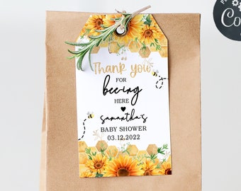 May include: A brown paper bag with a sunflower and bee themed thank you tag that reads "Thank you for bee-ing here for Samantha's Baby Shower 03.12.2022".