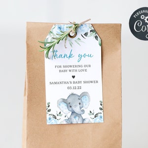 May include: A blue and white baby shower favor bag with a thank you tag featuring a cute elephant illustration and the text "Thank you for showering our baby with love Samantha's Baby Shower 03.12.22".