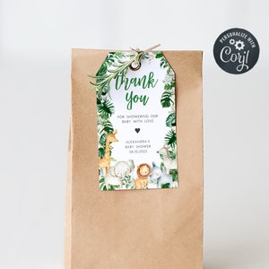 May include: A brown paper bag with a thank you tag attached. The tag has a jungle animal theme with a giraffe, lion, elephant, and zebra. The text on the tag reads "Thank you for showering our baby with love, Alexandra's Baby Shower, 04.10.2023".