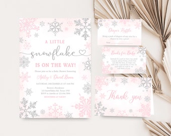 Könnte beinhalten: Ein Babyparty-Einladungsset mit Schneeflocken-Design. Die Einladung und die Karten zeigen rosa und silberne Schneeflocken auf weißem Hintergrund. Der Einladungstext lautet „A Little Snowflake Is On The Way!“ und enthält Details zur Veranstaltung.