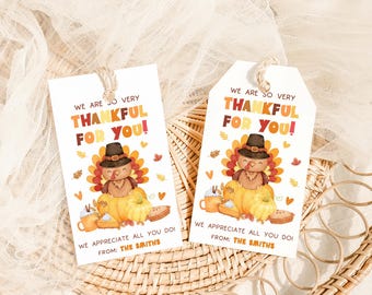 Peut inclure: Deux étiquettes cadeaux blanches de Thanksgiving avec une illustration de dinde, des citrouilles et le texte "WE ARE SO VERY THANKFUL FOR YOU!". Les étiquettes incluent également le texte "WE APPRECIATE ALL YOU DO! FROM: THE SMITHS". Chaque étiquette est attachée avec de la ficelle naturelle.