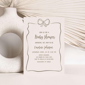 a baby shower card next to a white vase