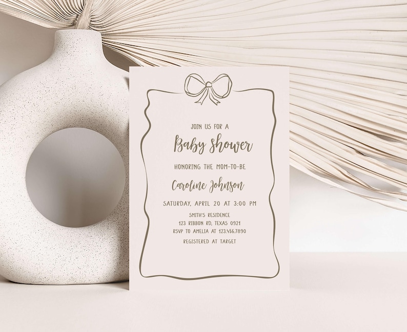 a baby shower card next to a white vase
