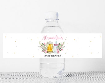 May include: A white water bottle with a pink and gold baby shower label. The label features a beer mug and a baby bottle with flowers and gold glitter. The text on the label reads "Alexandra's Baby Shower".