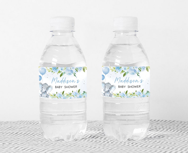 Op de afbeelding: Twee doorzichtige plastic waterflessen met blauwe en witte etiketten. De etiketten tonen een aquarel-illustratie van een babyolifant met blauwe ballonnen en bloemen. De tekst op de etiketten luidt "Maddison's Baby Shower".