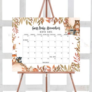 May include: A baby shower calendar on an easel, featuring a fall theme with woodland animals and autumn leaves. The calendar includes the text "Guess Baby Alexandra's Birth Date" and a calendar grid with the due date marked.
