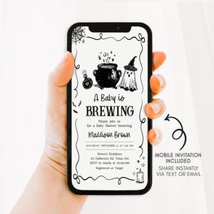 A hand holding a smartphone displaying an invitation for a baby shower.