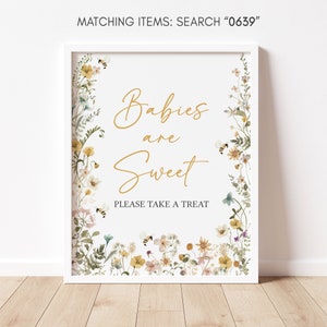 May include: A white framed sign with a floral border and the text "Babies are Sweet" in gold lettering. The sign also says "Please take a treat".