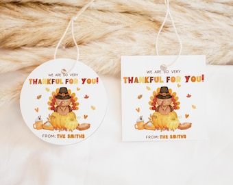Peut inclure: Étiquettes cadeaux de Thanksgiving avec une illustration de dinde. Les étiquettes sont blanches, une ronde et une carrée, avec le texte "WE ARE SO VERY THANKFUL FOR YOU!". Le texte "FROM: THE SMITHS" est également inclus.