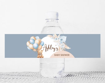 Może przedstawiać: Etykieta na butelkę wody na baby shower w kolorze niebieskim i beżowym z pluszowym misiem trzymającym balony, wzorem kwiatowym i tekstem "Baby Shower Ashley's".