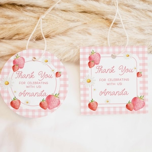 Puede incluir: Etiquetas de agradecimiento en vichy rosa y blanco con un diseño de fresa y margarita. El texto dice "Gracias por celebrar con nosotros! Amanda".