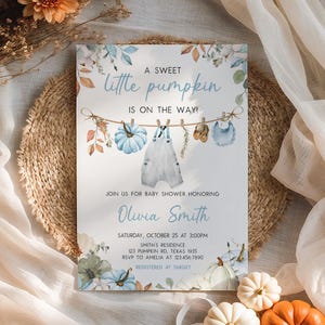 A baby shower invitation for a sweet little pumpkin baby shower, featuring a rustic and autumnal theme with illustrations of pumpkins, clothes, and flowers.