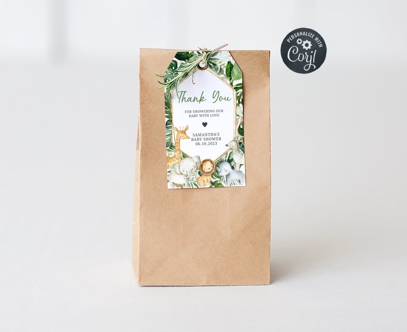 May include: A brown paper bag with a thank you tag attached. The tag has a green leafy border with a gold geometric frame. The text on the tag reads "Thank You for showering our baby with love" and "Samantha's Baby Shower 06.10.2023". There are illustrations of jungle animals on the tag.