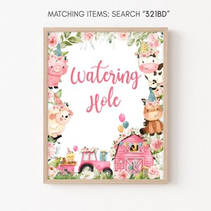 May include: A pink and white printable sign with the text "Watering Hole" surrounded by farm animals and flowers. The sign is framed in a light brown frame.
