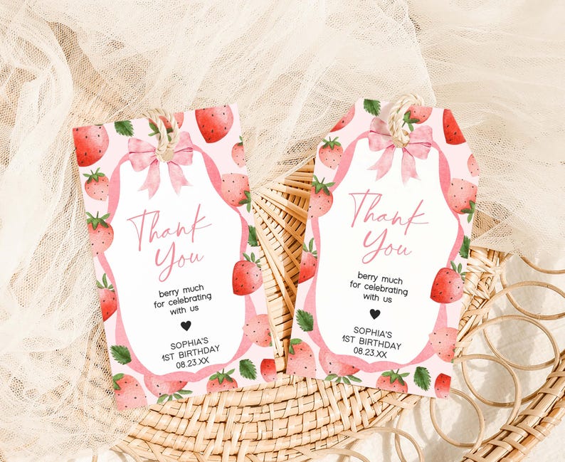 two tags with strawberries on them sitting on a wicker basket