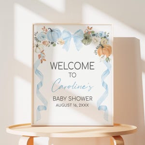 Könnte beinhalten: Gerahmtes Babyparty-Schild mit dem Text "WELCOME TO Caroline's BABY SHOWER AUGUST 16, 2XXX". Es zeigt Aquarellkürbisse, Blumen und eine blaue Schleife. Hellblaue Bänder fallen an den Seiten herab.